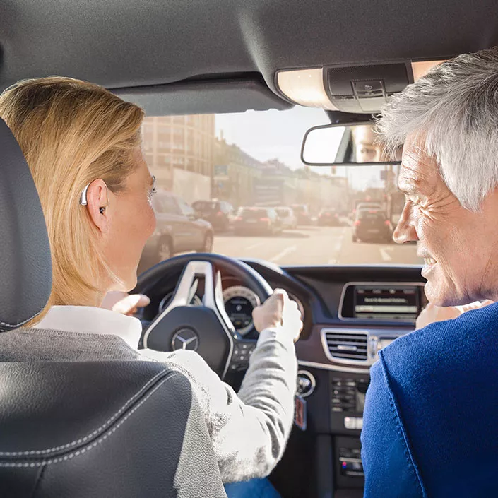 Frau am Steuer mit Hörgeräten im Ohr